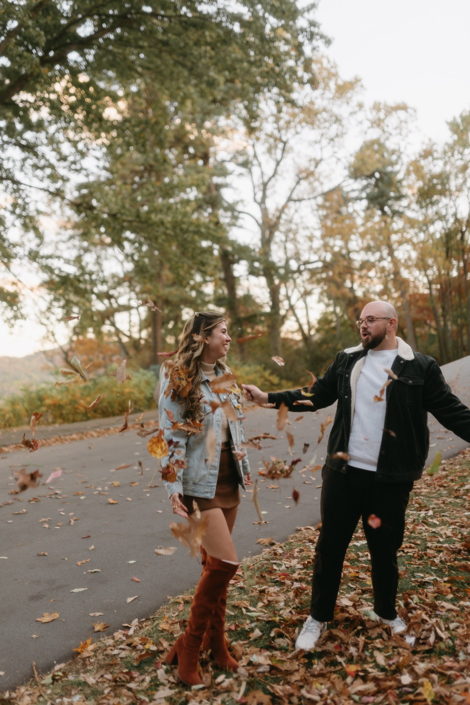 Nicole and Ian tossing leaves at each other at the edge of the parkway.