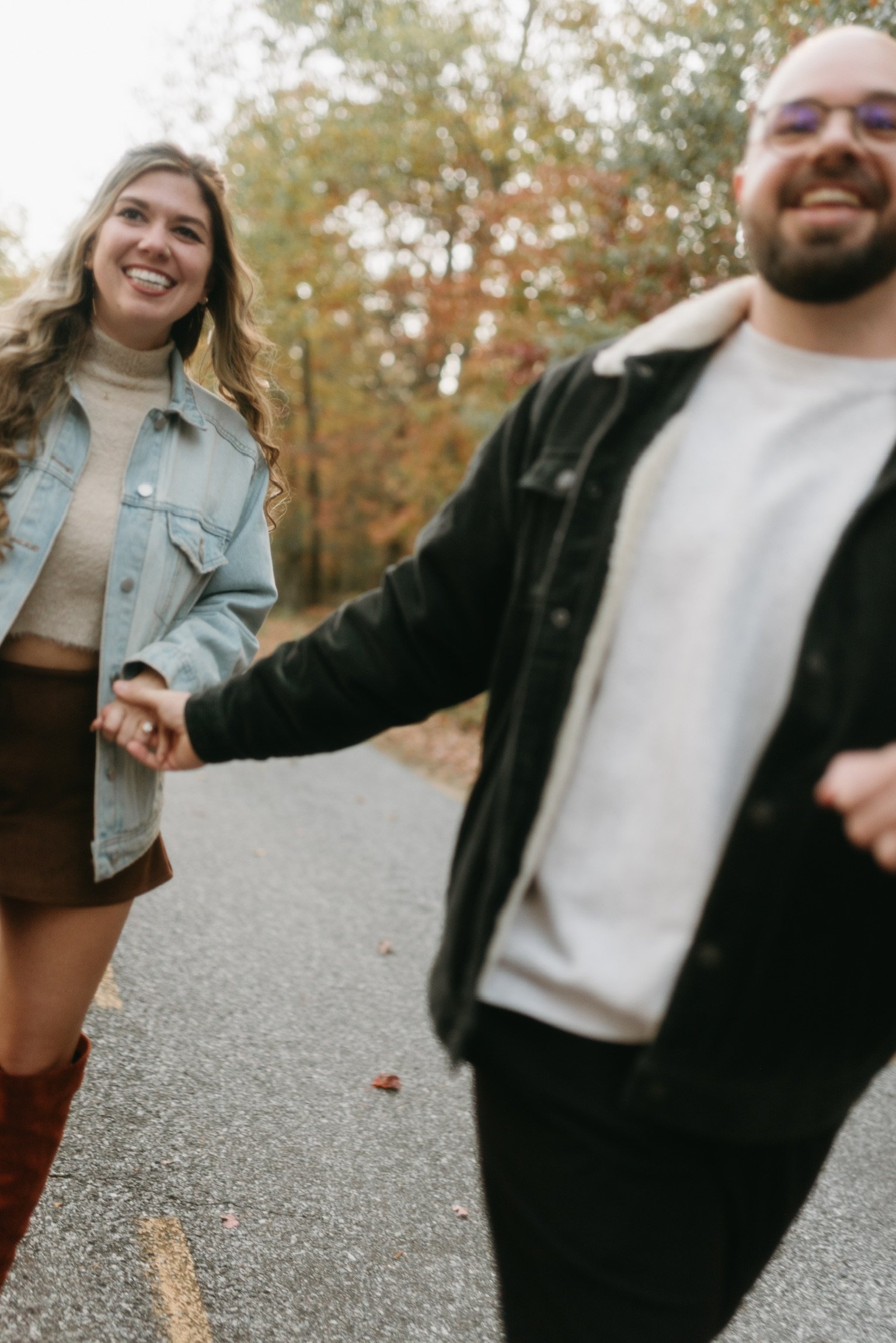 Nicole laughing as Ian leads her along the road by the hand.