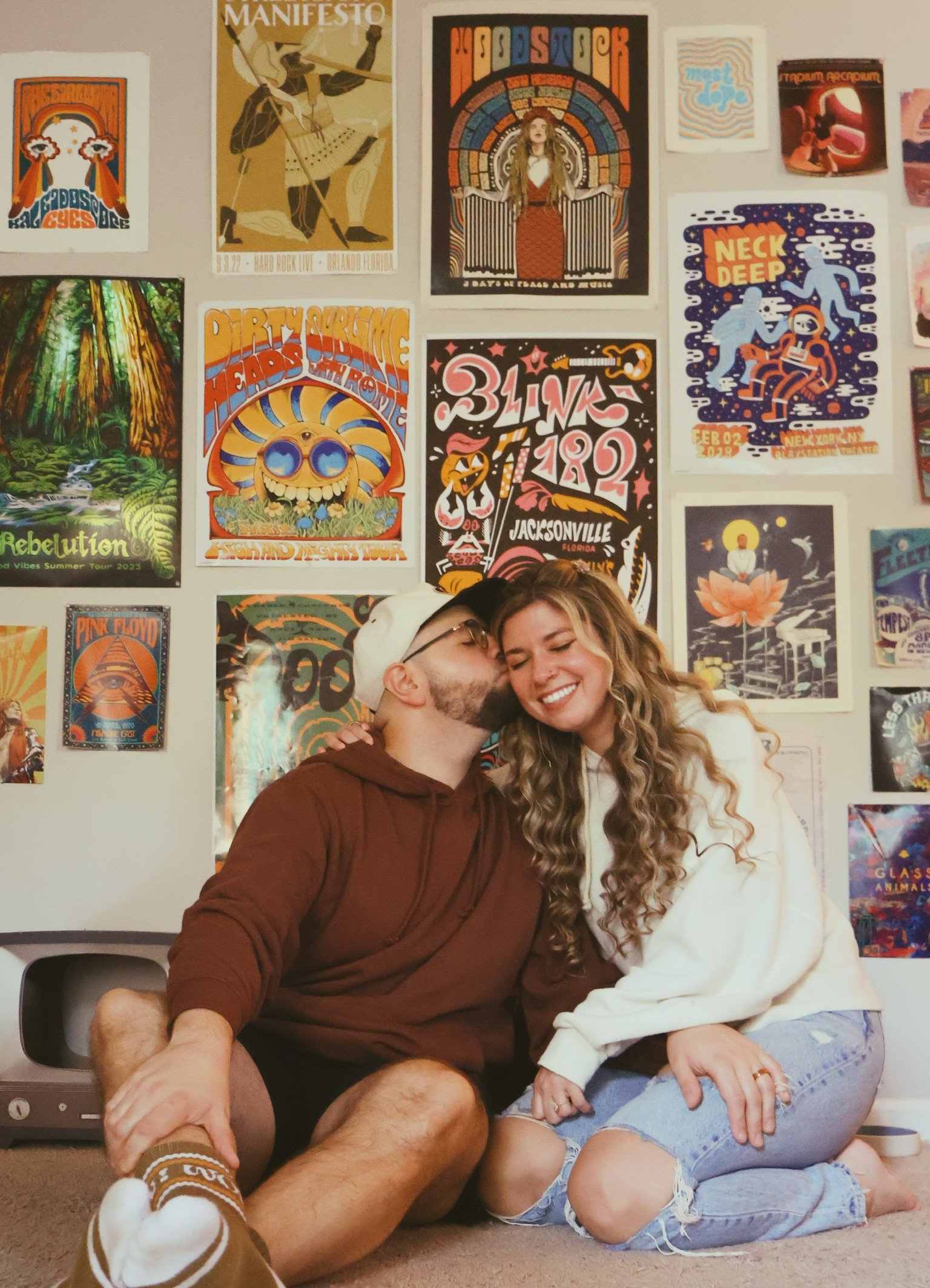 Ian kissing Nicole’s temple in front of the gig-poster wall.