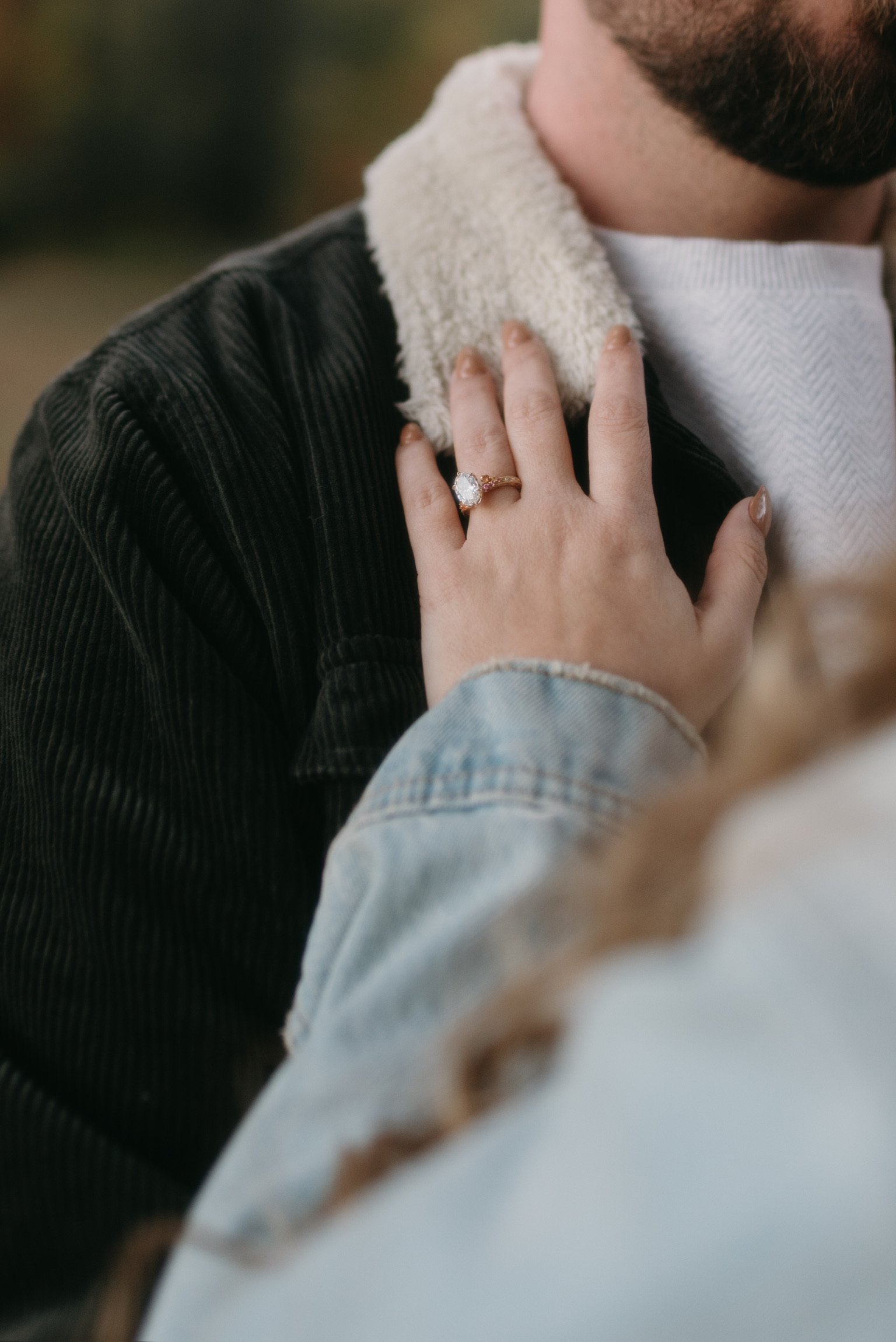 Close up: Nicole’s ringed hand resting on the fleece collar of Ian’s jacket.