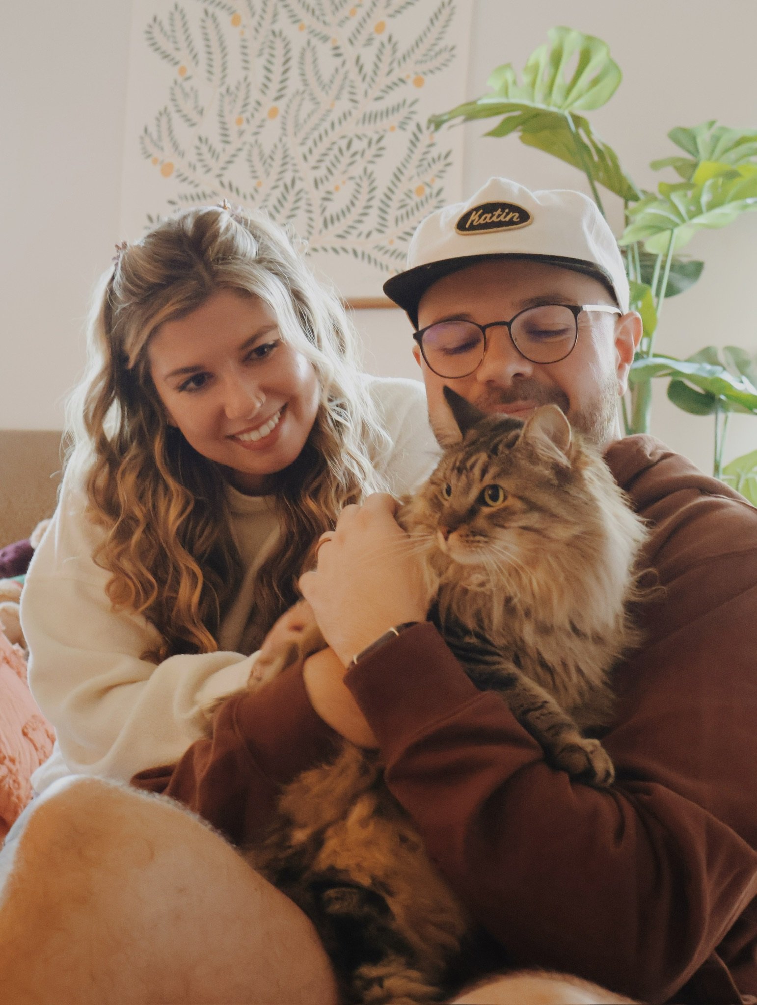 Nicole and Ian close together, smiling down at the cat in Ian’s arms.