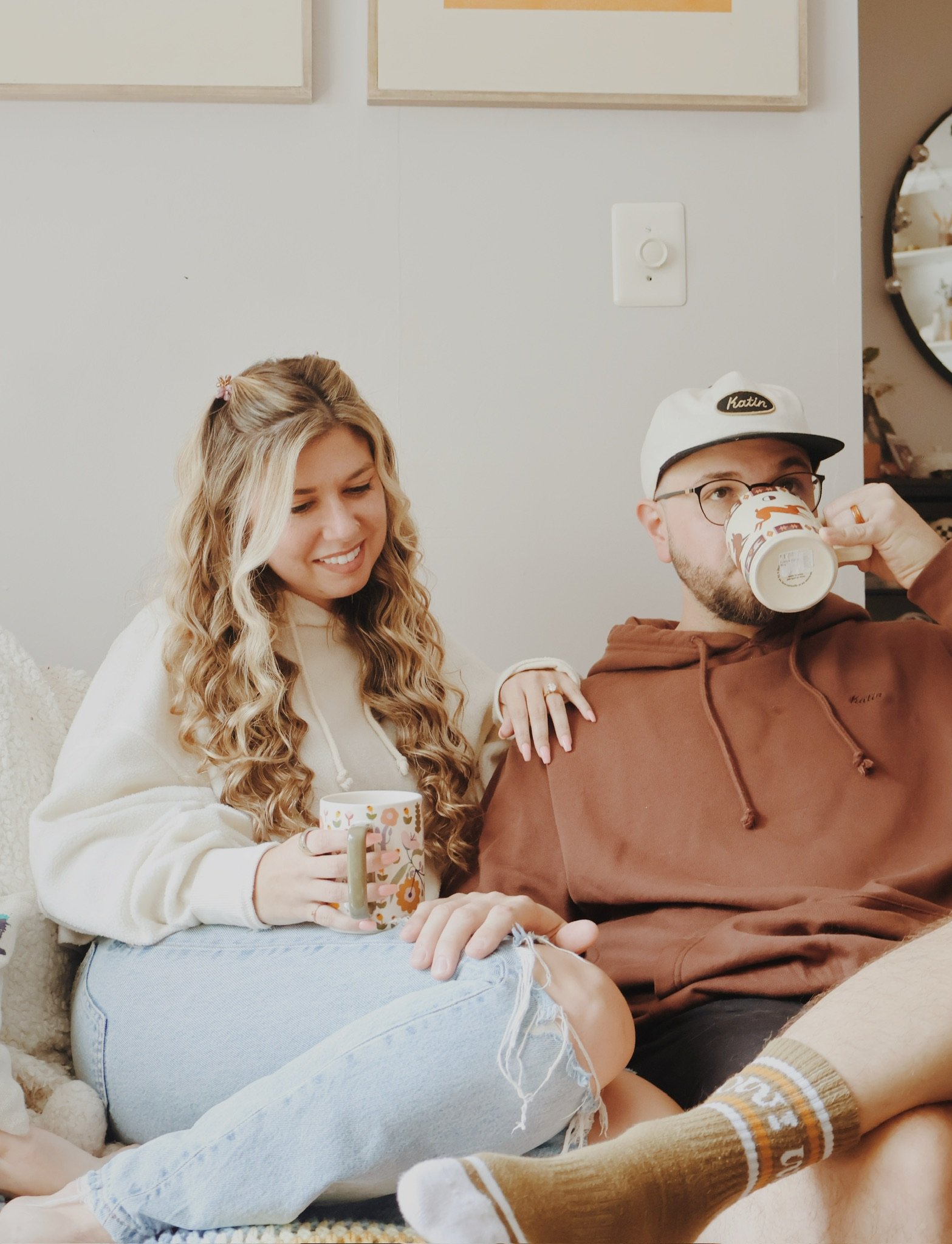 Nicole leaning into Ian on the couch as he sips from a mug.