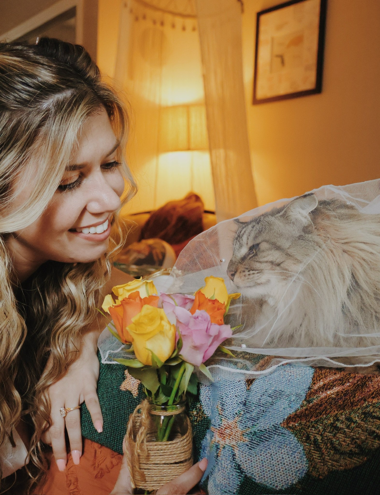 Nicole smiling at the veiled cat, a jar of roses in her hand.