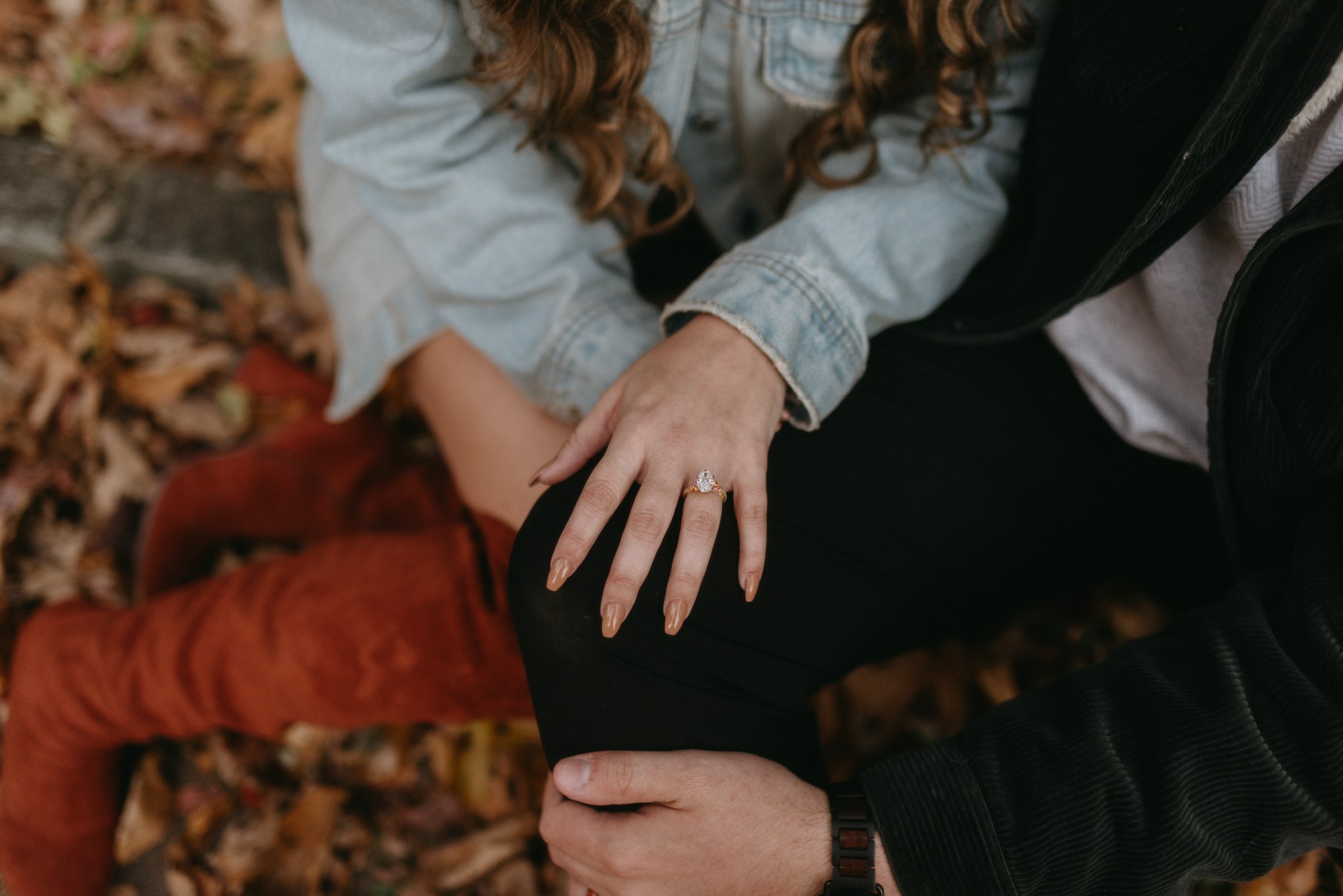 Close up: Nicole’s ringed hand resting on Ian’s knee.