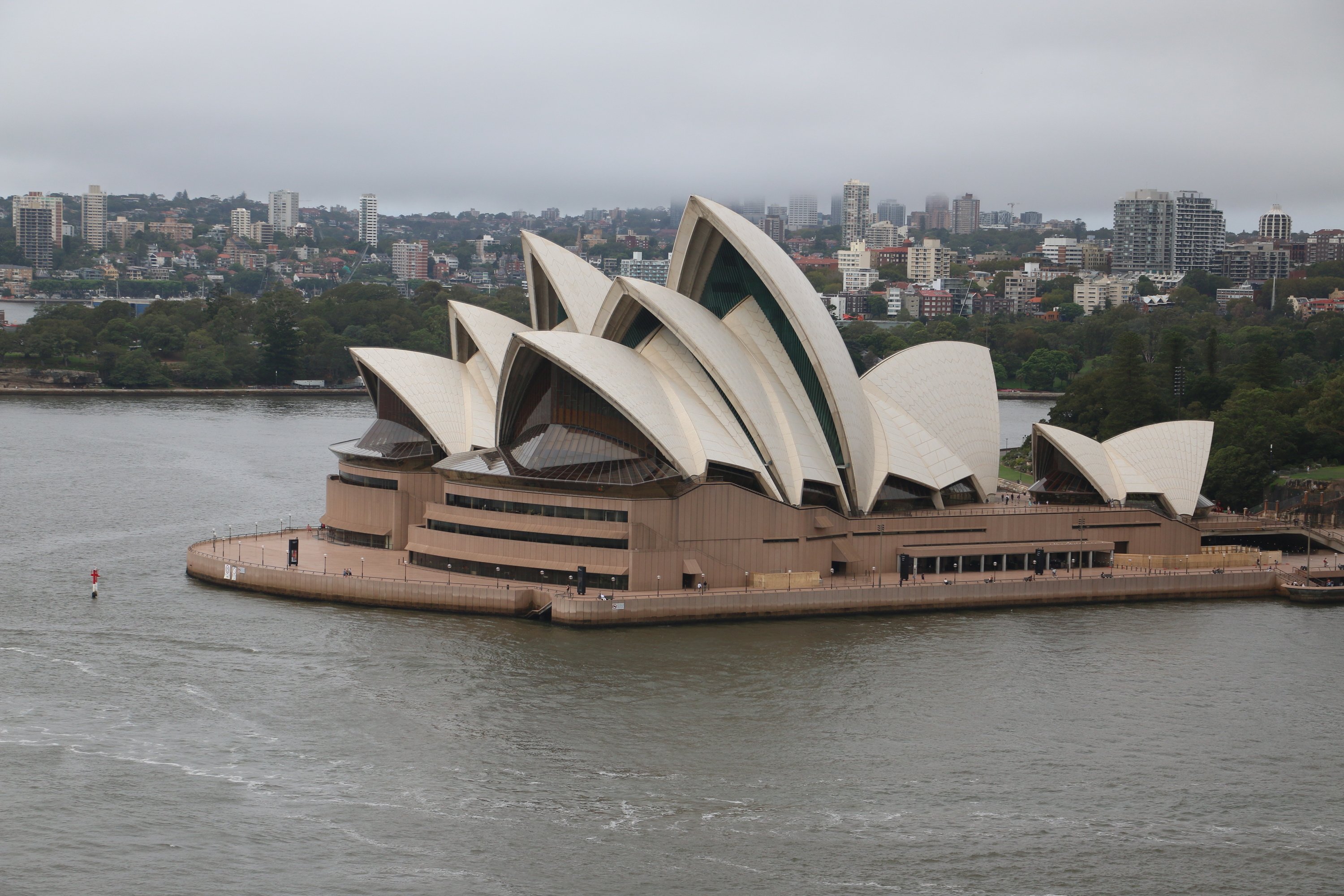 The Sydney Opera House from across the harbor on a gray day.